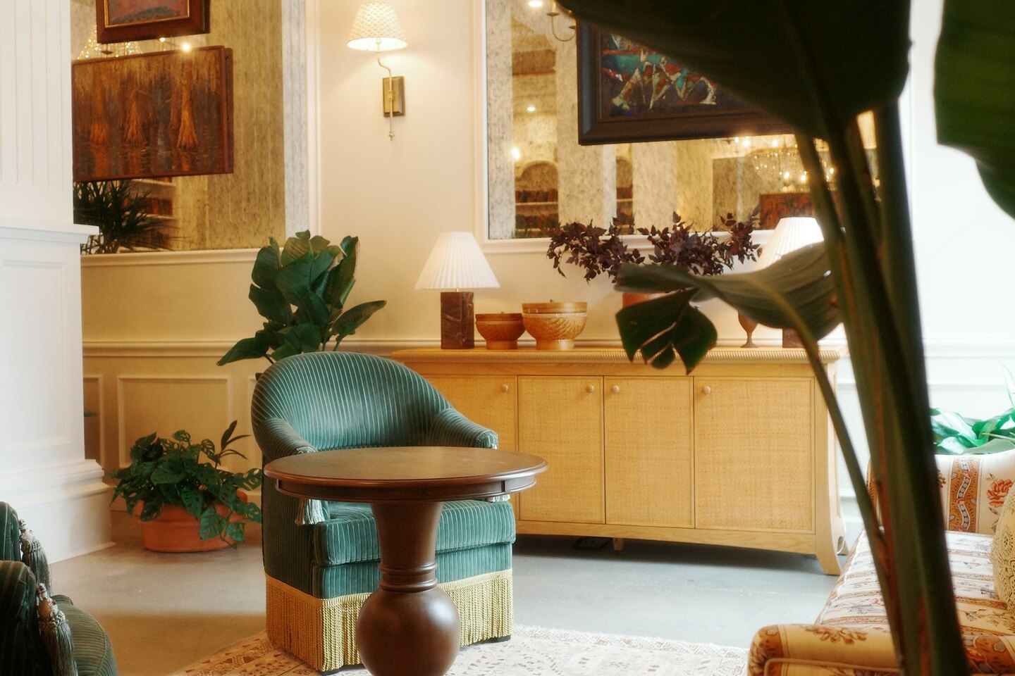 Elegantna hotelska avla z zelenimi naslanjači, sobnimi rastlinami in toplimi svetilkami