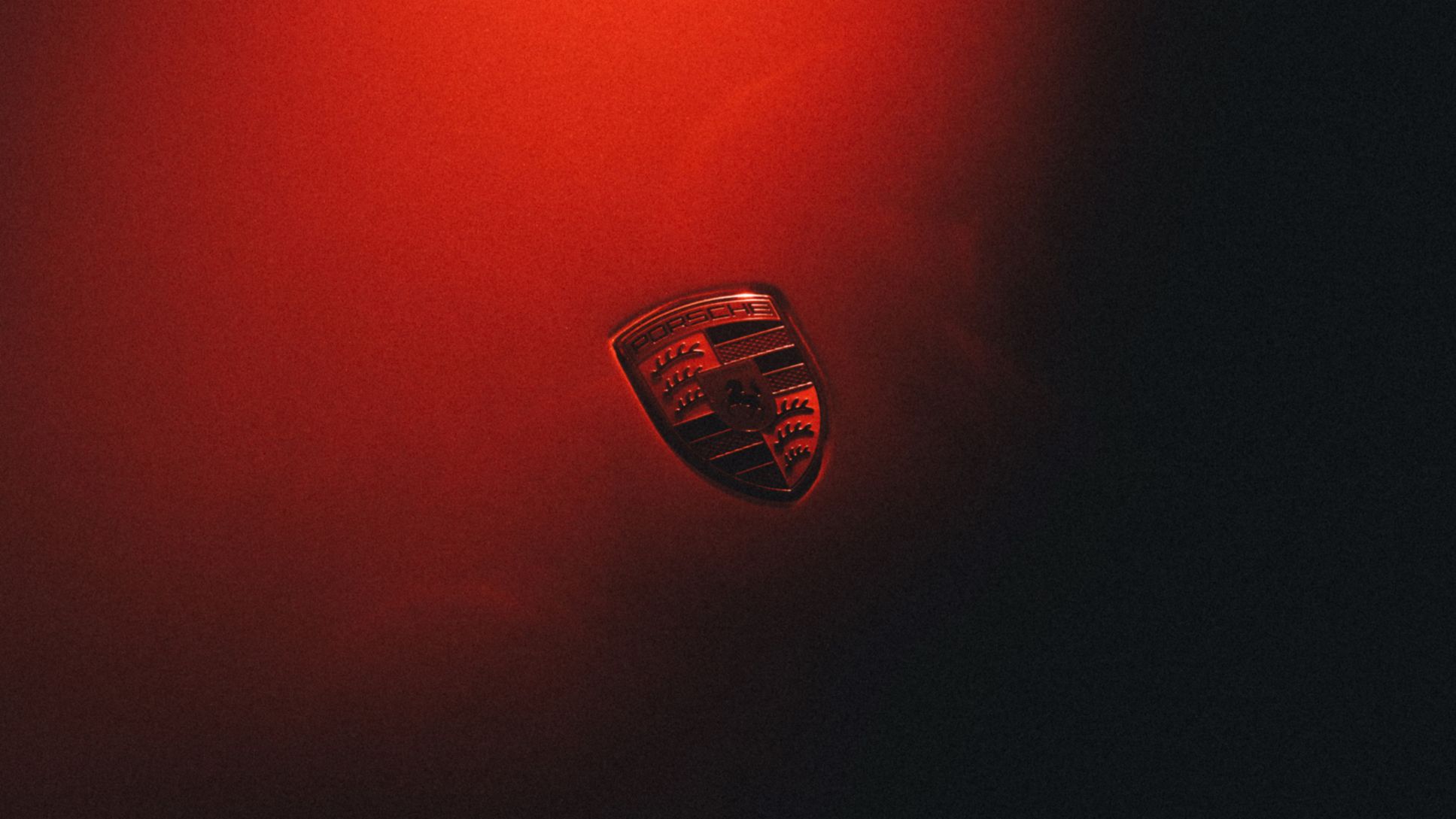 Porschejev grb v rdeči svetlobi na temnem ozadju